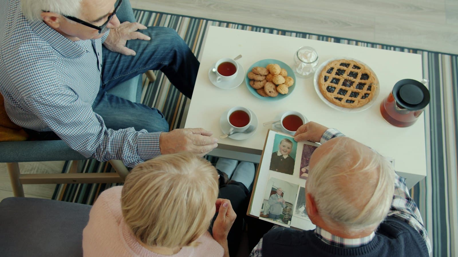Friends looking through an old photo album over tea